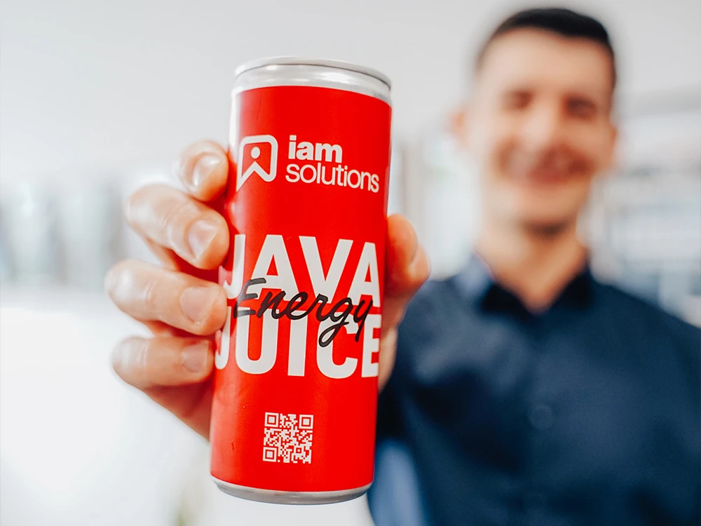 Mitarbeiter der Uhl Werbeagentur hält eine rote Dose mit der Aufschrift ‚Java Juice‘ und dem Logo von iam solutions.